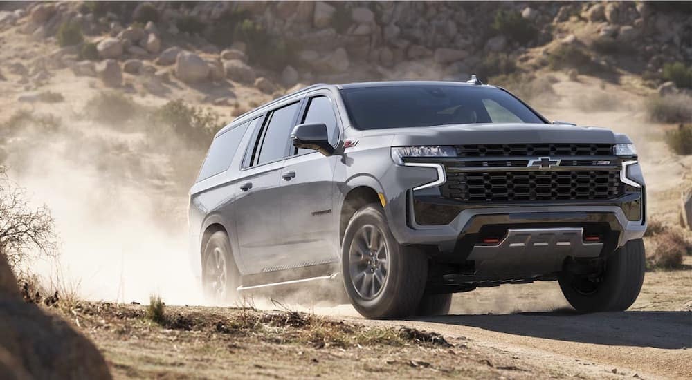 A grey 2024 Chevy Suburban Z71 is shown driving off-road from a Chevy dealer near Webster City.