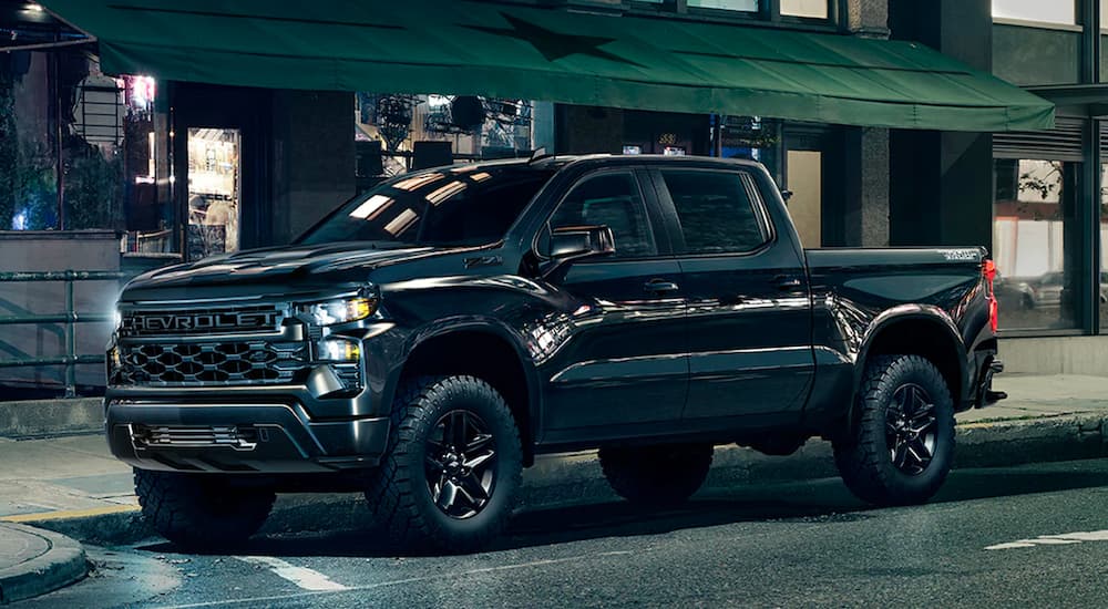 A black 2023 Chevy Silverado 1500 Midnight Trailboss Z71 is shown parked on a city street.