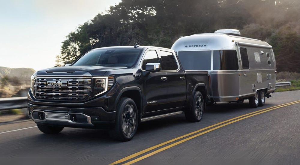 A black 2024 GMC Sierra 1500 Denali towing a trailer.