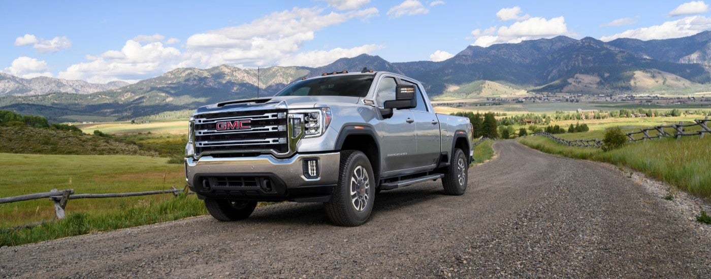 A silver 2023 GMC Sierra 2500HD is shown driving on a cloudy day.