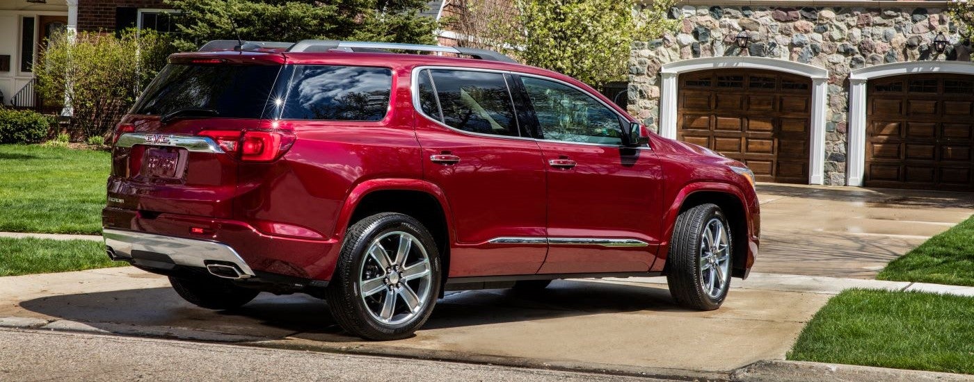A red 2018 GMC Acadia Denali is shown parked on a driveway after leaving a used GMC dealer.