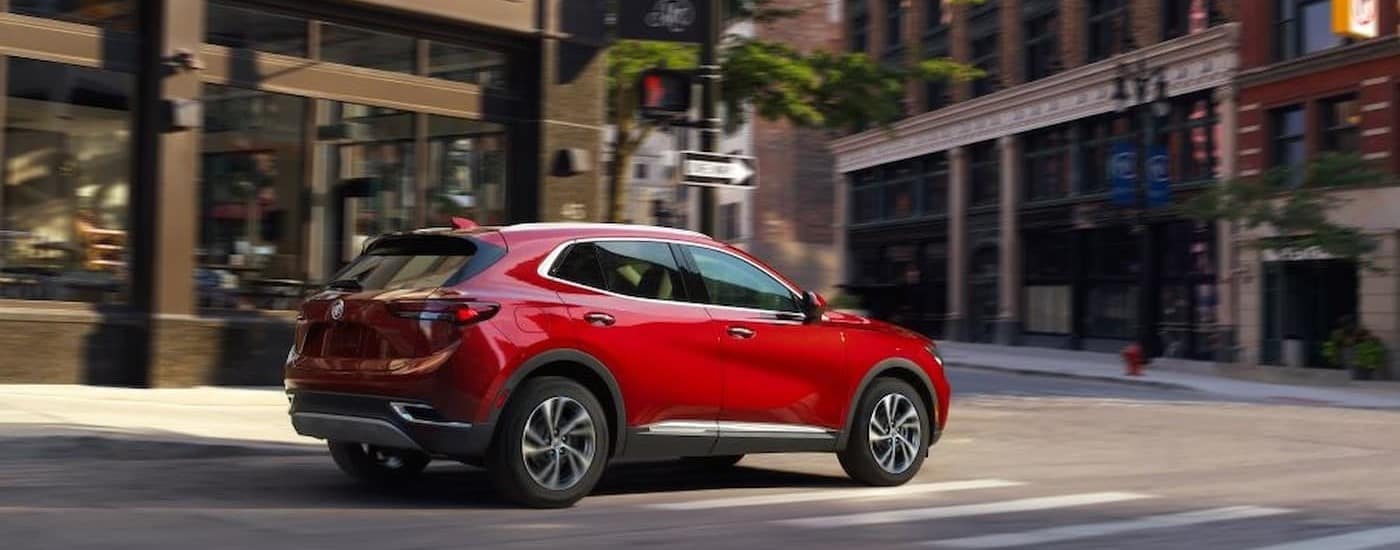 A red 2023 Buick Envision is shown driving on a city street.