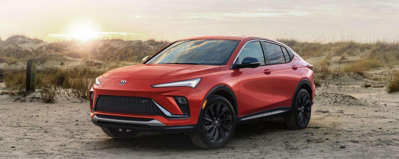 A red 2024 Buick Envista ST parked off-road in a desert.
