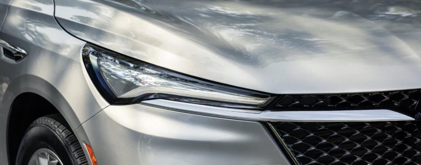 A close-up on the headlight of a silver 2023 Buick Enclave Avenir is shown.