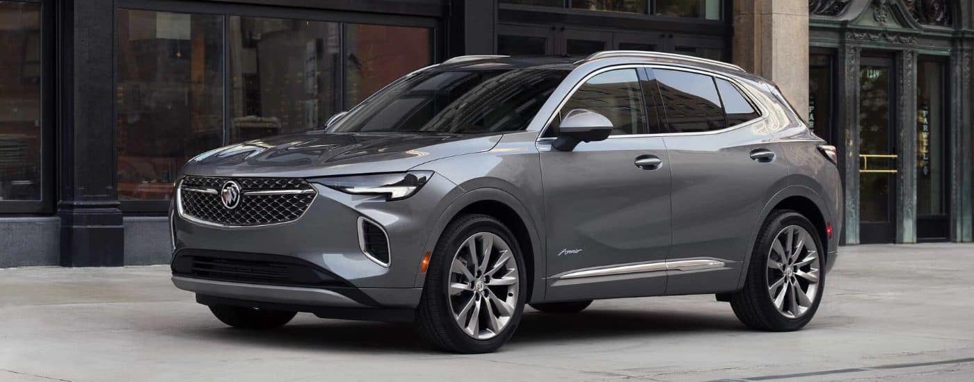 A grey 2023 Buick Envision Avenir is shown parked near a building.