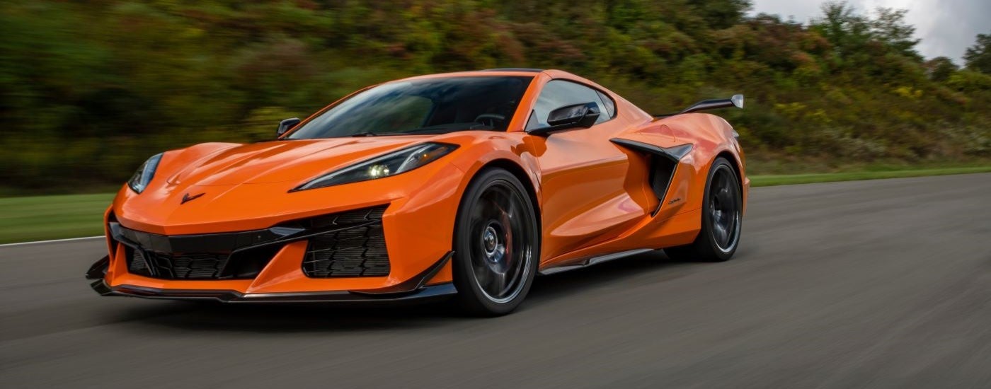 An orange 2023 Chevy Corvette Z06 is shown driving on an open road.