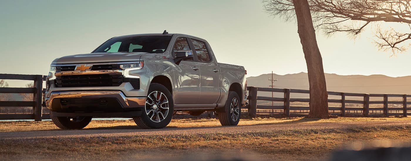 A silver 2024 Chevy Silverado 1500 Z71 parked near a fence on a farm.