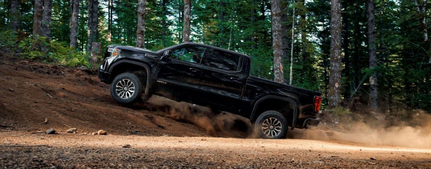 A black 2019 GMC Sierra 1500 AT4 is shown from the side off-roading after leaving a GMC Dealer near Humboldt.